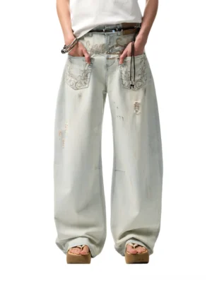 Light blue distressed arc-leg wide-leg jeans shown from a low angle with vintage acid wash, embroidered front pockets, and an oversized streetwear silhouette