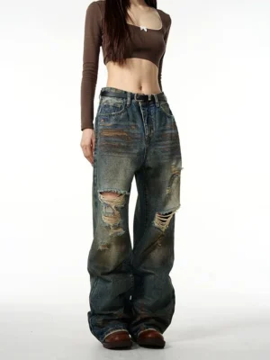 Female model wearing vintage blue distressed baggy ripped jeans with wide legs and knee rips in a front full-body streetwear outfit