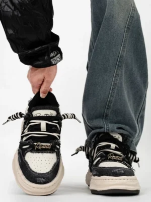 Distressed black and off white platform skate sneakers with layered canvas upper mixed laces and chunky cream sole styled with baggy blue jeans and a black quilted jacket