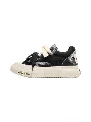Black and white distressed tie dye canvas platform sneakers shown in a side view with a thick white sole and streetwear low top silhouette