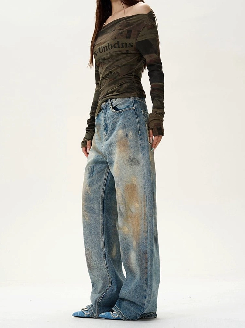 Side view of relaxed distressed blue baggy jeans featuring a defined waistband, roomy wide-leg cut, and straight denim hem
