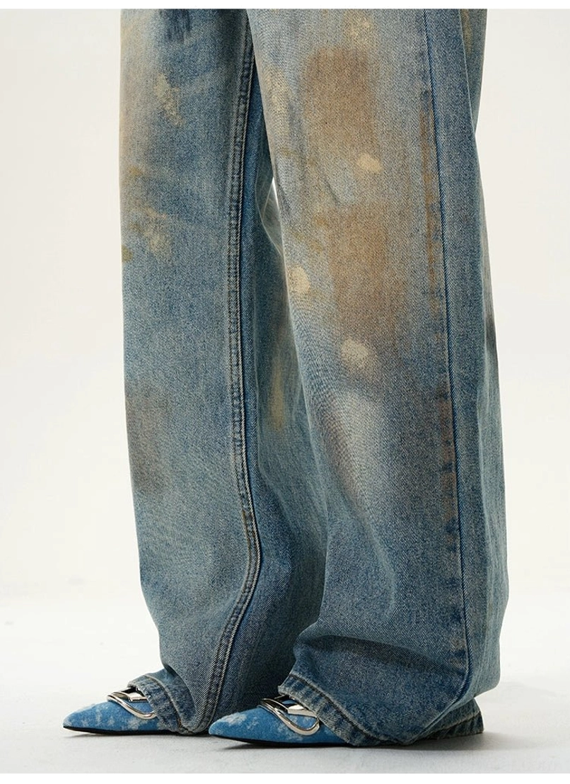 Close-up view of wide straight denim hems on distressed blue baggy jeans with visible stitching and vintage wash details