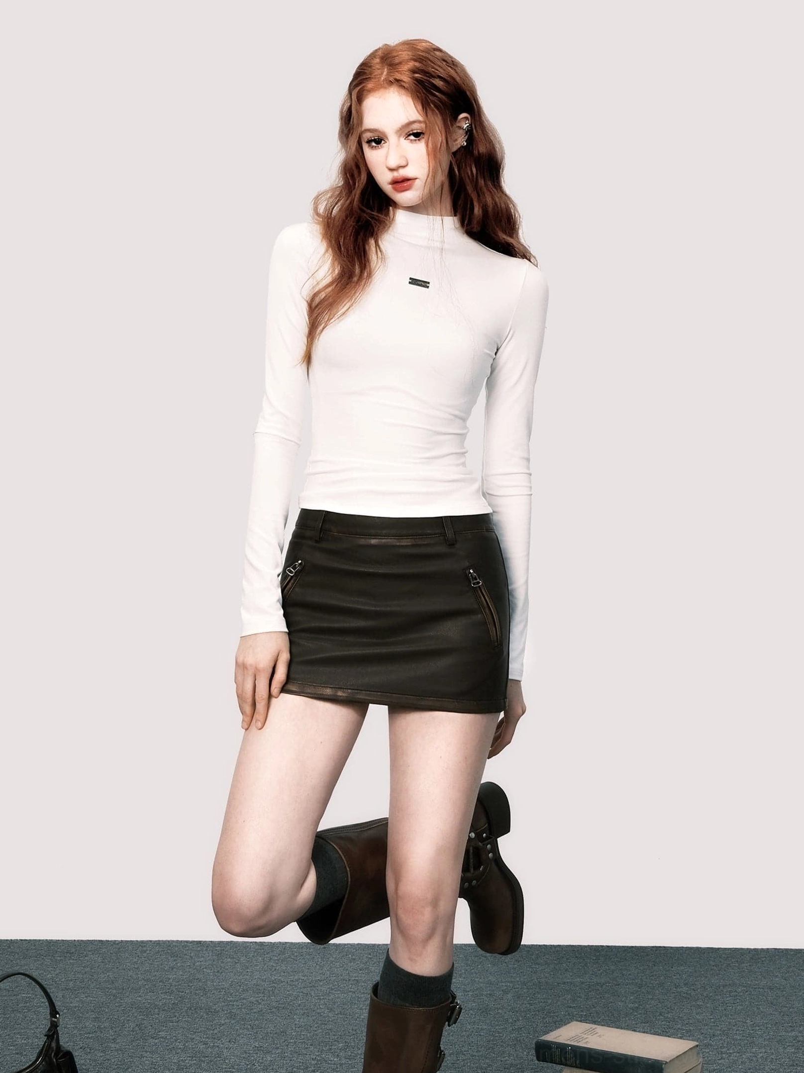 Distressed brown faux leather fitted mini skirt styled with white turtleneck top and brown knee-high boots