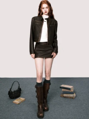 Distressed brown faux leather moto jacket and matching mini skirt styled with white turtleneck and brown knee-high boots front view