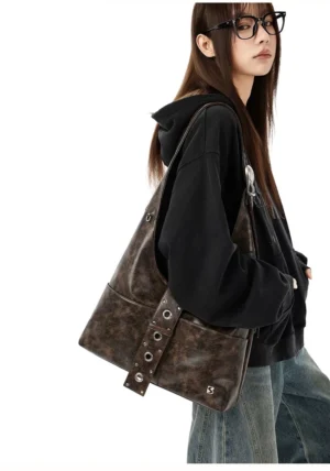 Distressed coffee brown rivet harness hobo shoulder bag worn with black graphic hoodie and baggy streetwear jeans rear view