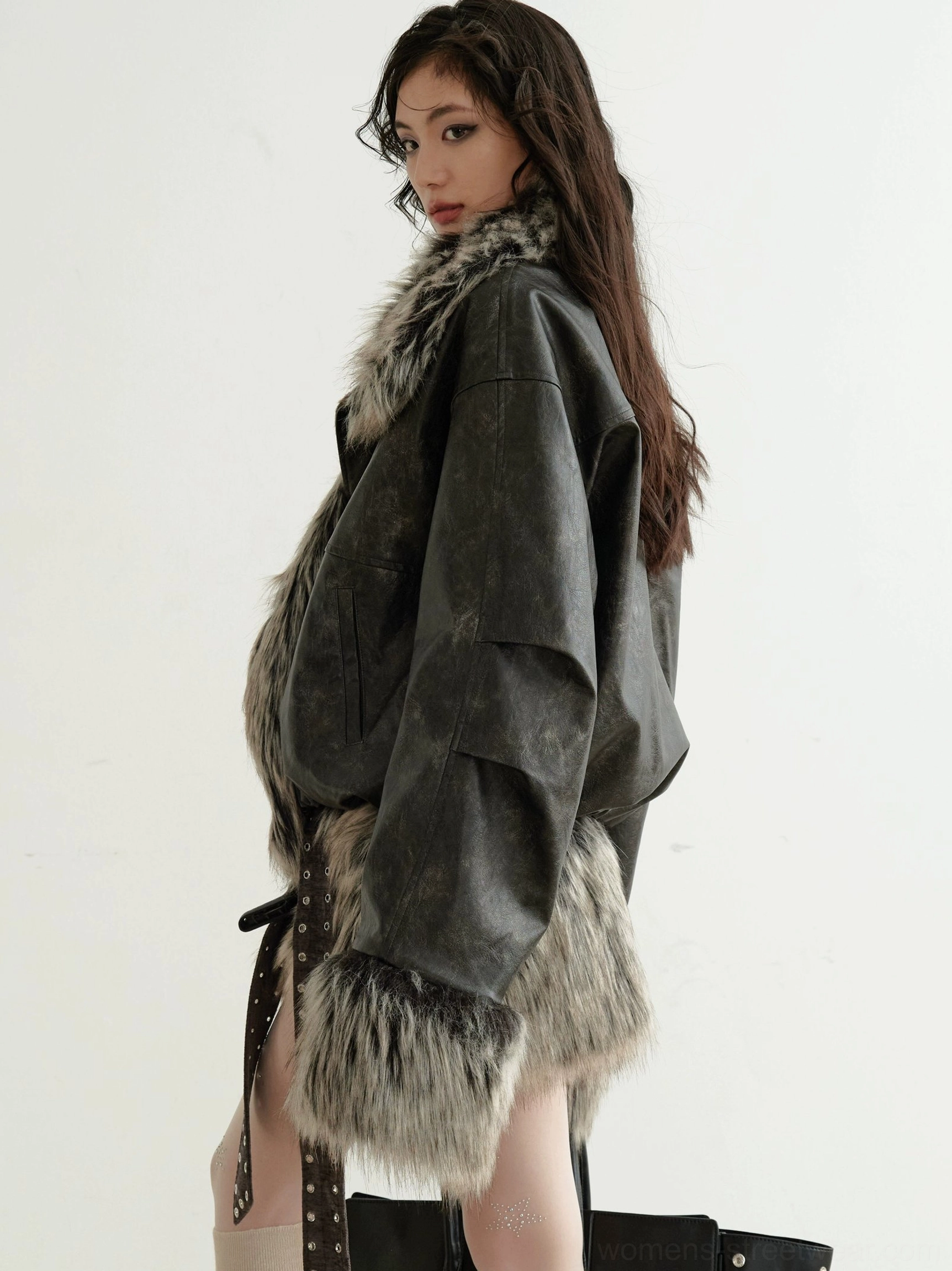 Close-up side view showing the distressed leather-look texture fluffy faux fur cuffs hem and decorative straps on a cropped jacket