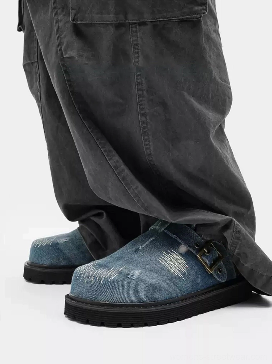 Side view of distressed denim buckle platform mule clogs styled with stacked dark gray cargo pants and textured denim upper