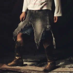 Close-up of faded distressed denim chaps shorts with uneven frayed hem and visible blue denim underlayer