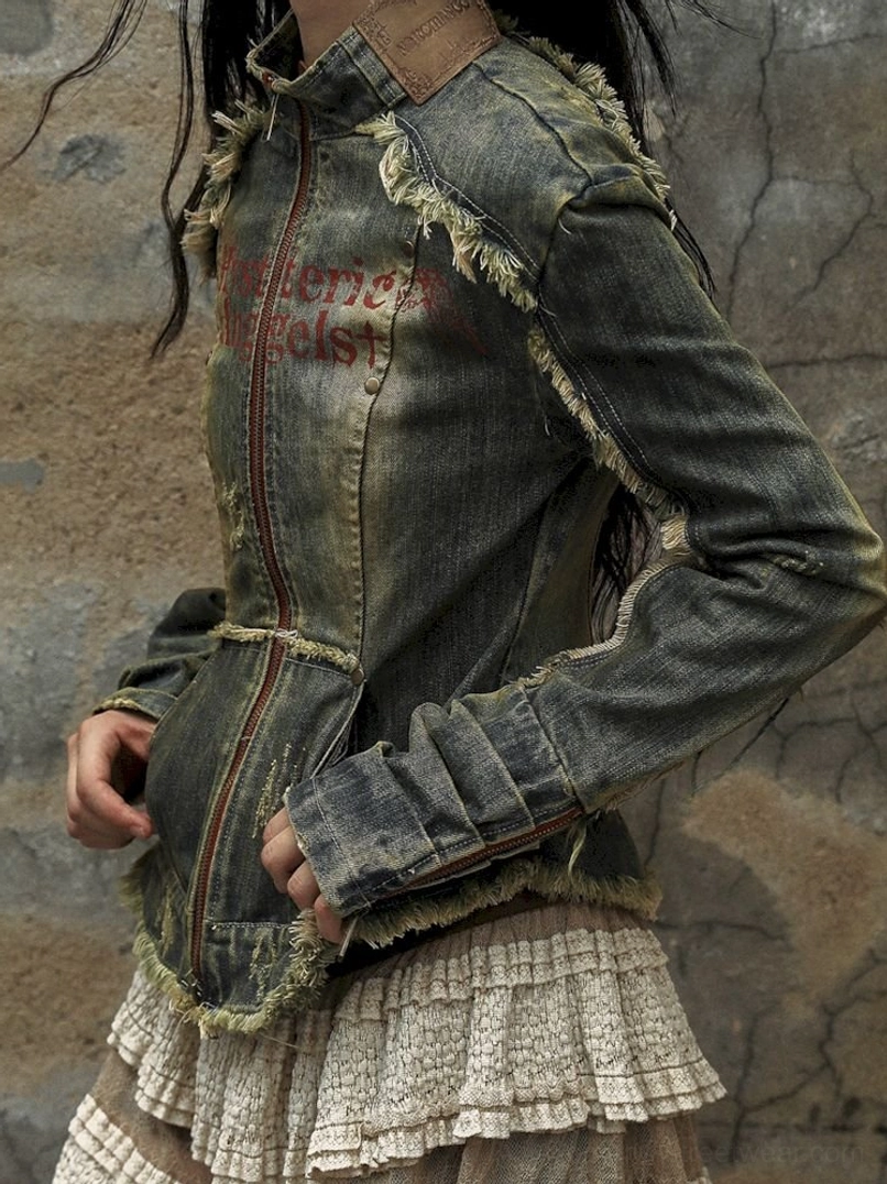 Close-up of faded distressed denim corset jacket with front zipper, red printed detail, raw edges, and lace skirt trim