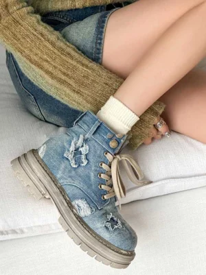 Model wearing distressed blue denim platform combat boots with white crew socks and denim shorts in a Y2K streetwear outfit