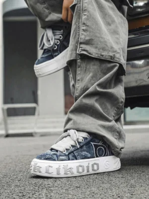Distressed denim platform skate sneakers styled with gray cargo pants on asphalt for a casual streetwear outfit