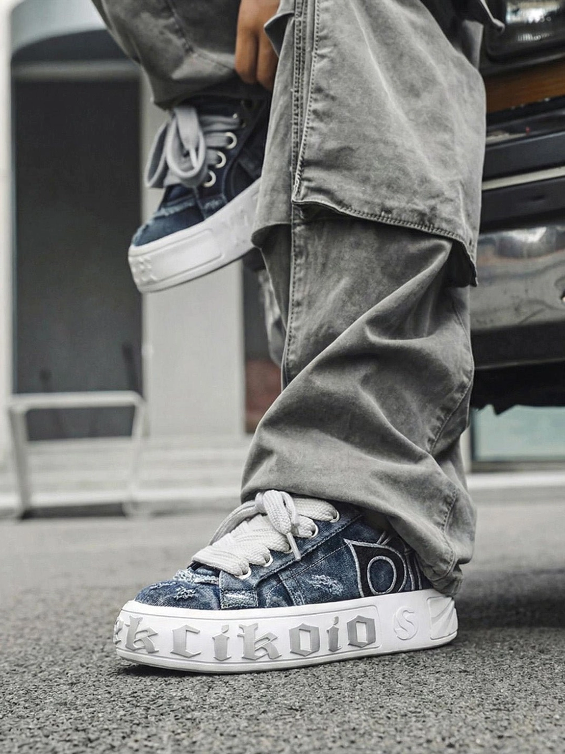 Distressed denim platform skate sneakers styled with gray cargo pants on asphalt for a casual streetwear outfit