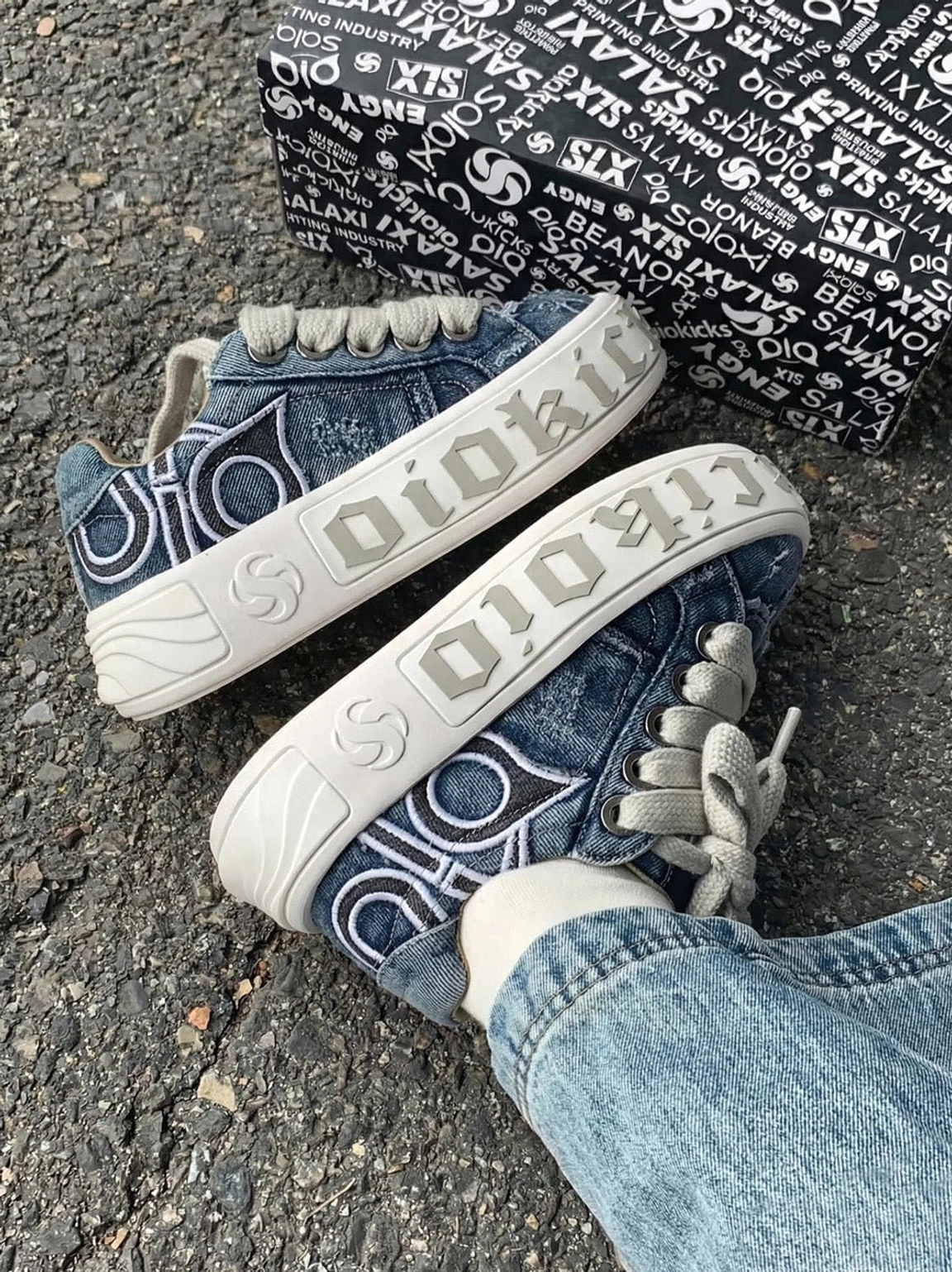 Angled view of distressed denim platform sneakers beside a shoe box with blue jeans for a relaxed streetwear outfit