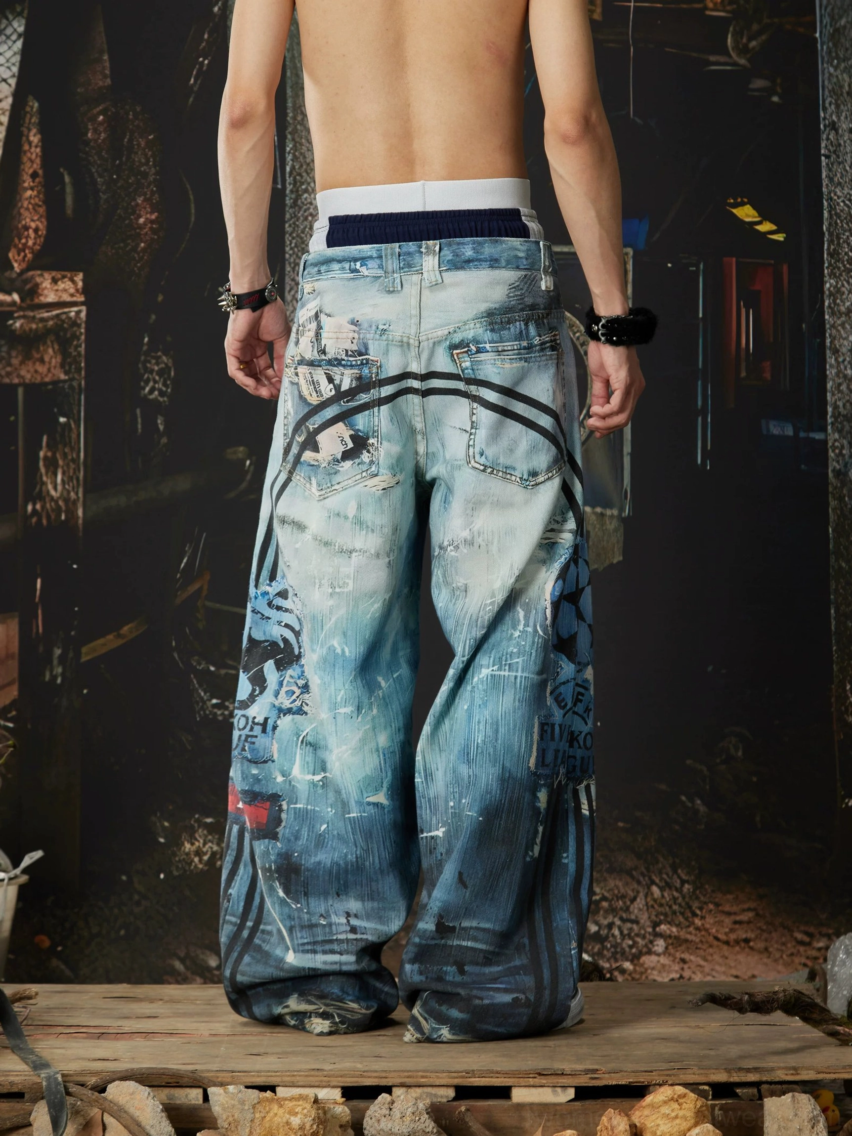 Rear view of ocean-wash distressed wide-leg jeans showing faded denim, back pocket styling, side graphics, and relaxed streetwear fit