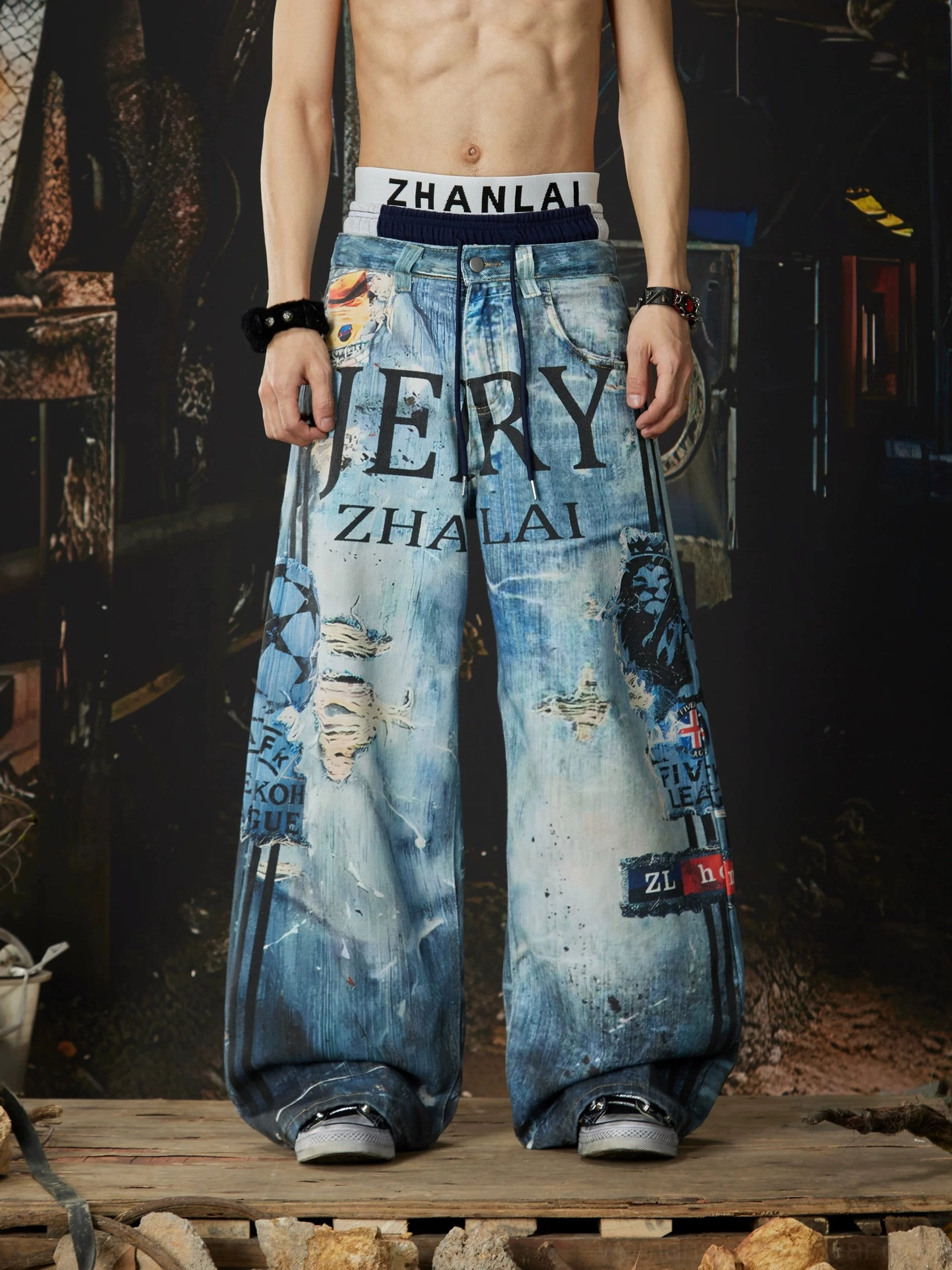 Front full-body view of distressed graffiti wide-leg jeans featuring bold JERY ZHALAI lettering, ripped patches, and faded vintage denim texture