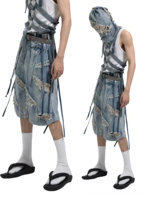 Side and front view of vintage blue distressed denim Bermuda shorts with hanging harness straps and raw frayed panels
