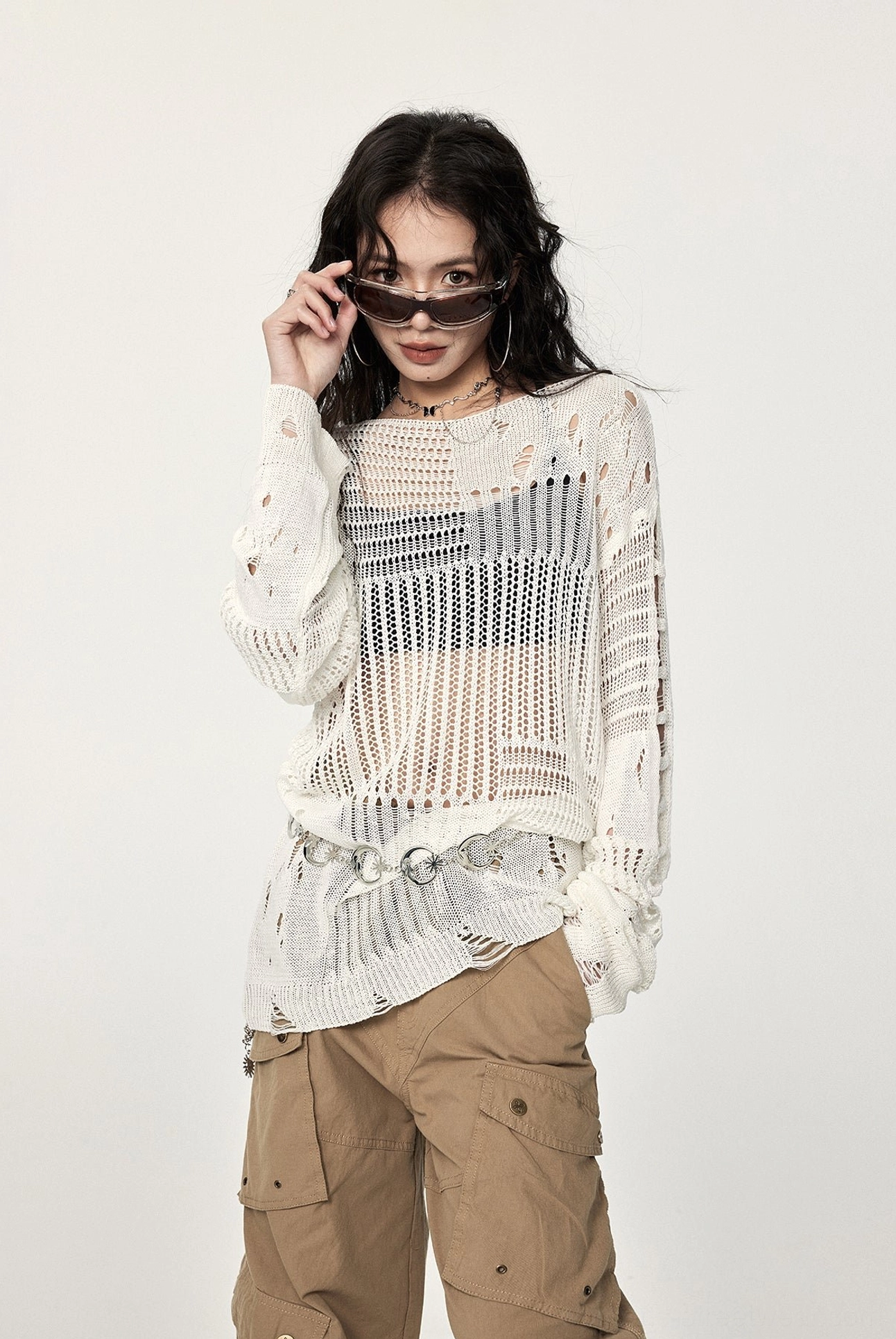 Side view of an airy distressed hollow-out crochet sweater featuring ripped sleeves, relaxed oversized shape, and neutral off-white knit finish