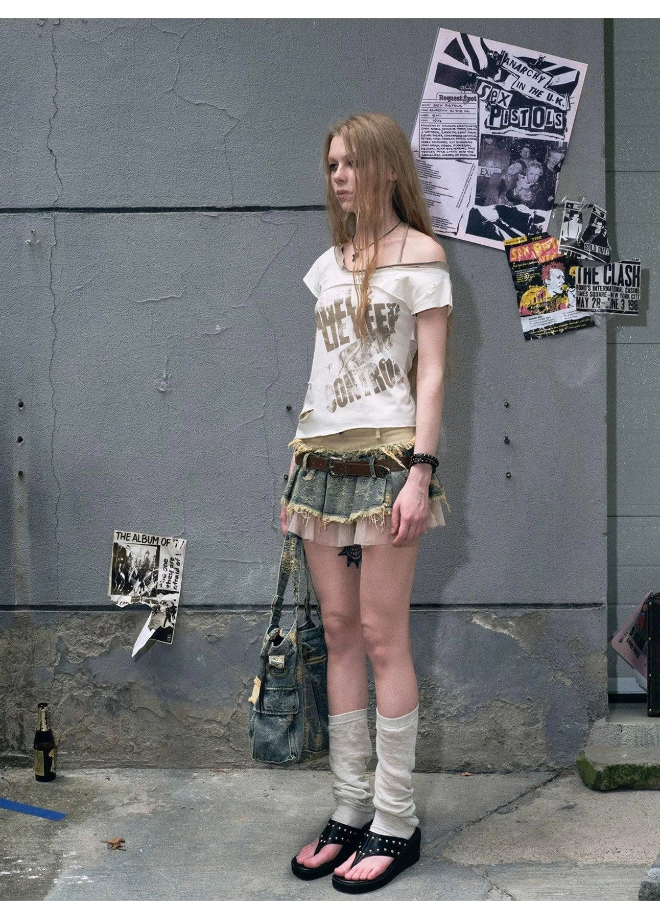 Distressed layered denim mini skirt with vintage brown belt, raw edge detailing, sheer tulle hem, and contemporary streetwear styling