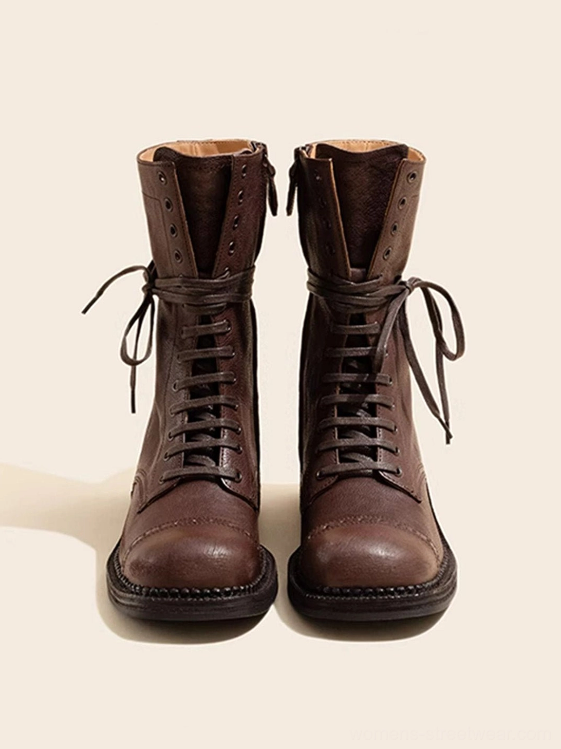 Front view of distressed leather mid-calf lace-up combat boots with brogue-inspired toe cap and folded shaft