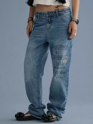 Front three-quarter view of blue distressed letter print straight-leg streetwear jeans with relaxed fit and acid wash denim