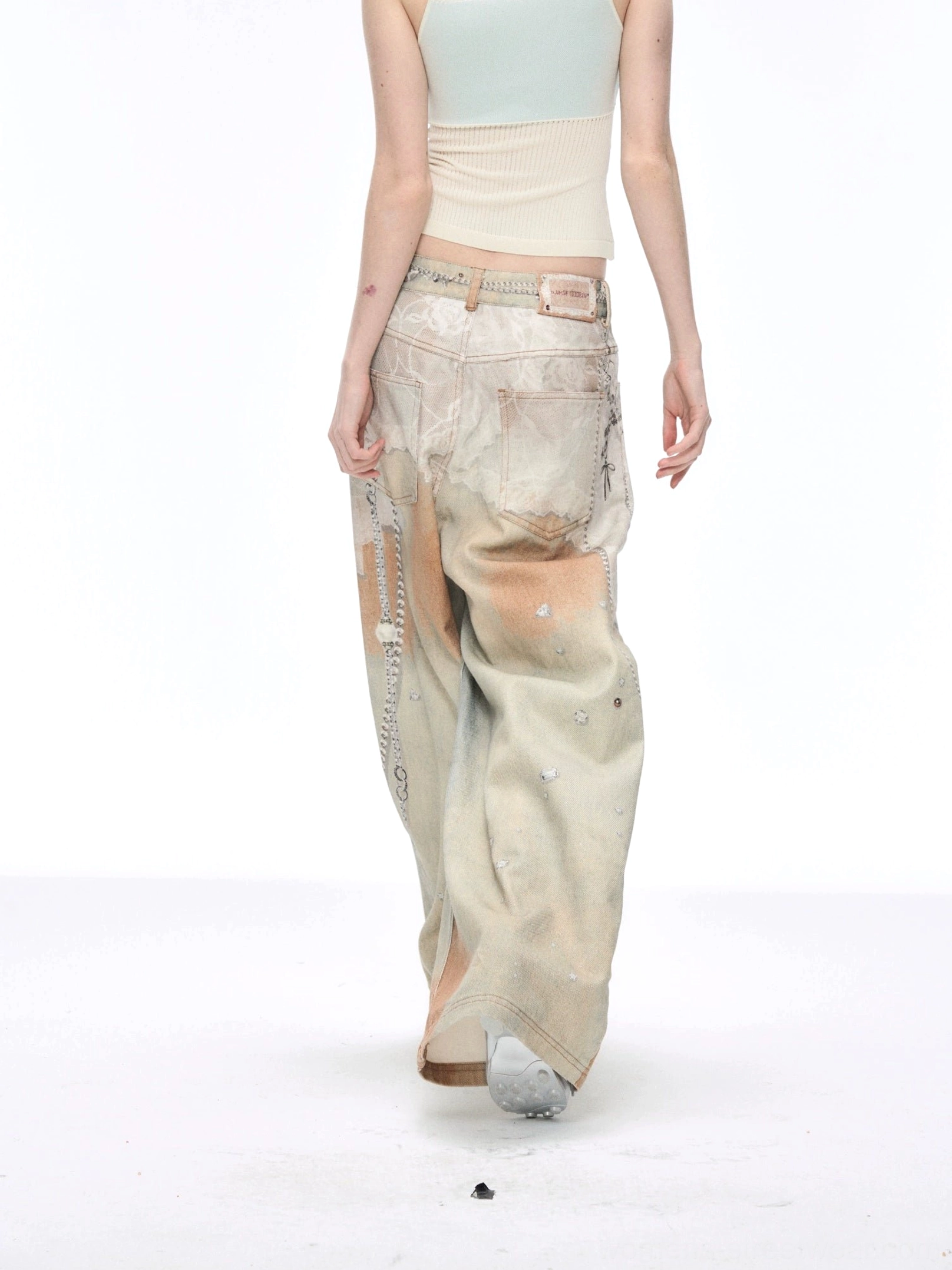 Rear view of vintage blue distressed painted wide-leg jeans showing back pockets faded wash loose leg silhouette and side chain accent