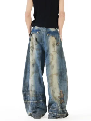 Rear view of distressed patchwork balloon wide-leg jeans with buttoned back pockets, faded thigh panels, relaxed oversized fit, and raw frayed hems