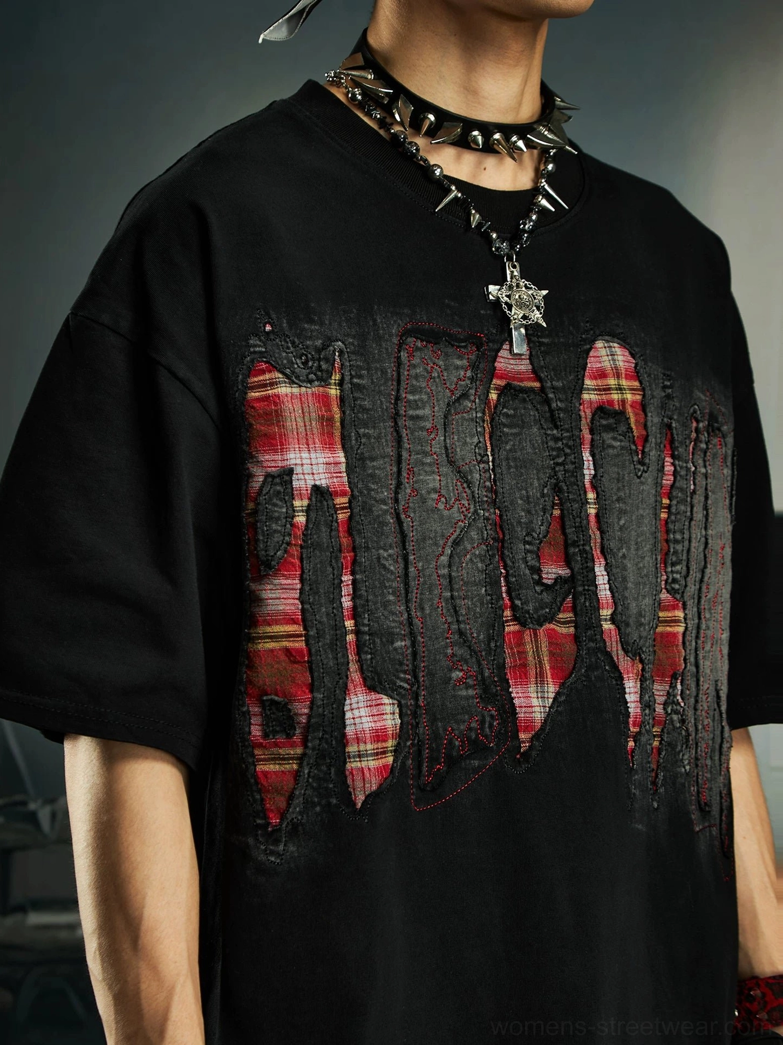 Close-up of black distressed plaid slash oversized graphic streetwear tee with layered red plaid chest lettering