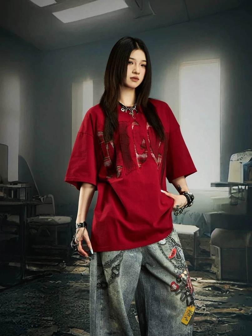 Red distressed plaid slash oversized graphic streetwear tee worn with embroidered wide-leg jeans in a vintage studio