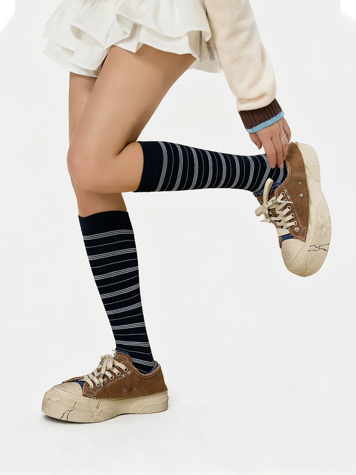 Distressed platform sneakers styled with a white mini skirt and striped socks for Korean streetwear fashion