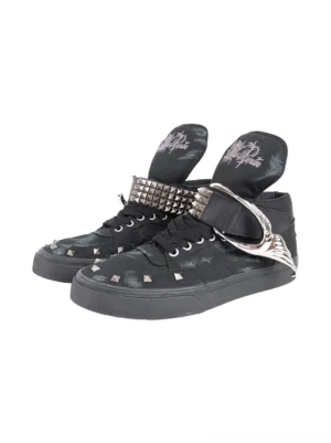 Front three-quarter view of black distressed studded high-top canvas sneakers with pyramid toe studs, wing-shaped metal hardware, adjustable ankle straps, and tonal rubber soles