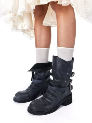 Women wearing distressed black triple-buckle ankle boots with white socks and a ruffle lace skirt