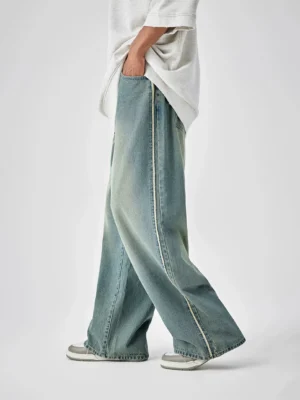 Distressed vintage blue wide-leg denim jeans shown from a low left-side angle with contrasting side stripe trim and an oversized grey streetwear t-shirt