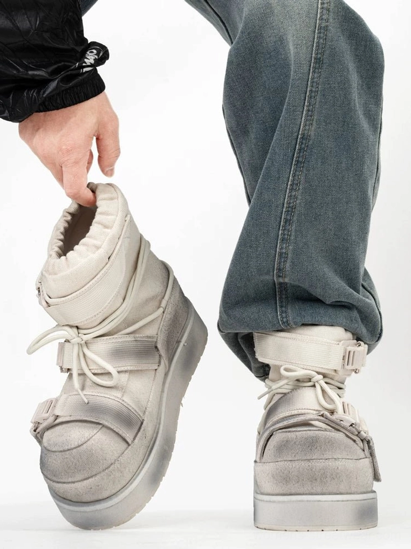 Distressed white platform snow boot worn with jeans, side on-foot view showing washed padded upper, buckle straps and thick rubber platform