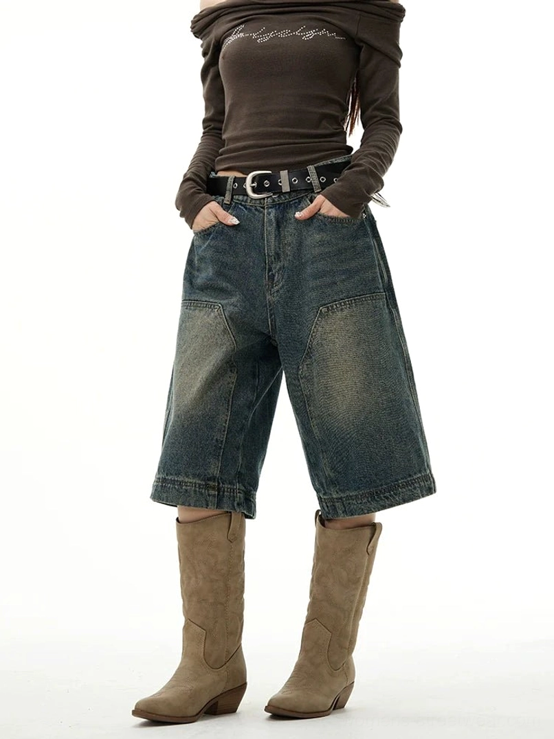 Side-front view of vintage distressed wide-leg denim Bermuda shorts with oversized utility pockets and a loose comfortable streetwear silhouette