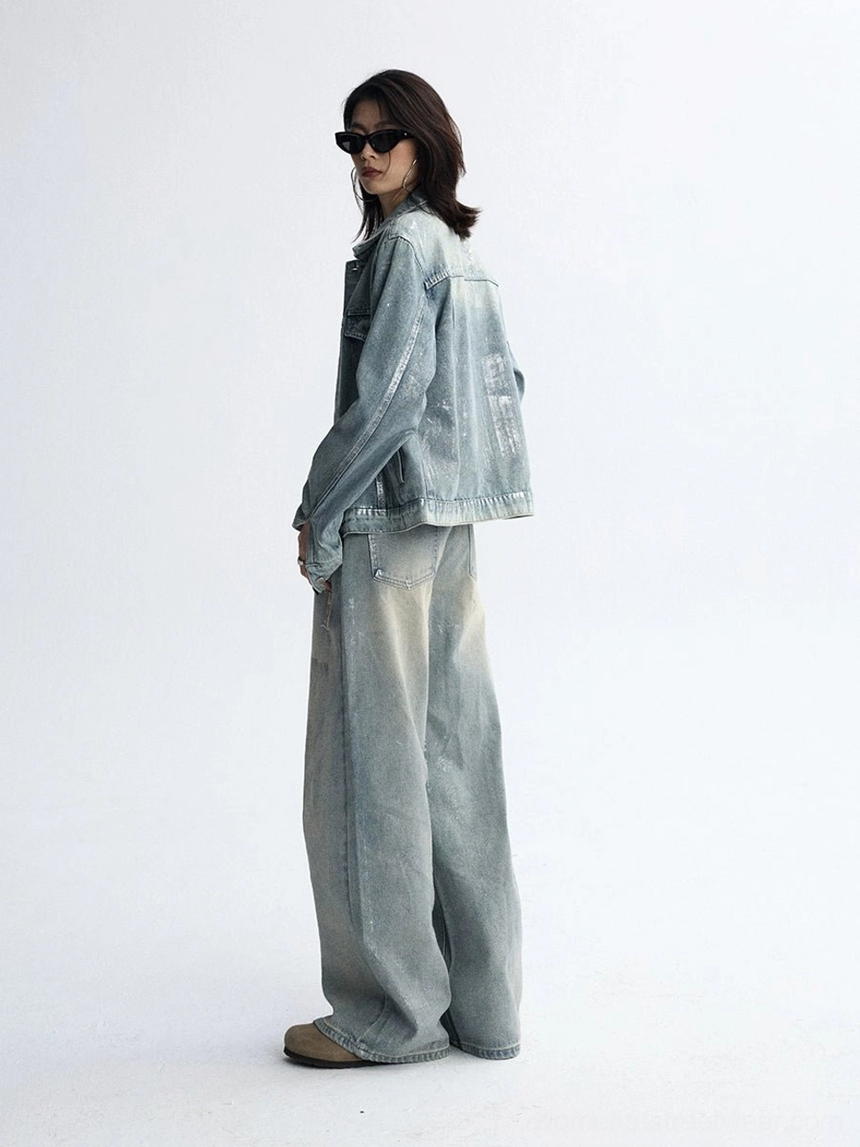 Back view of a denim streetwear outfit showing the relaxed wide-leg silhouette and faded light blue wash of the jeans