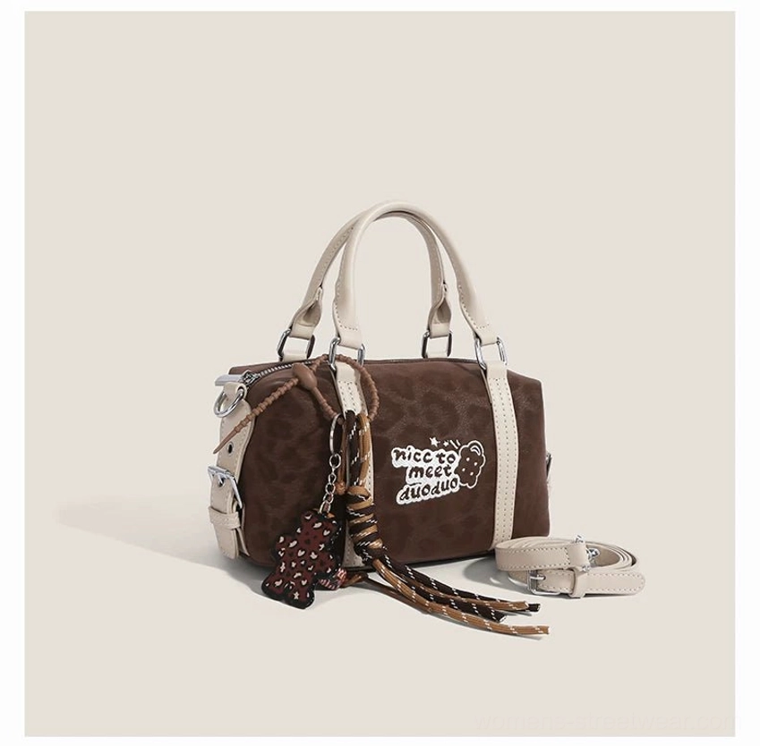 Dark brown leopard Doodle Charm streetwear barrel bag showing contrast handles, zipper top, embroidered patch and tassel charm