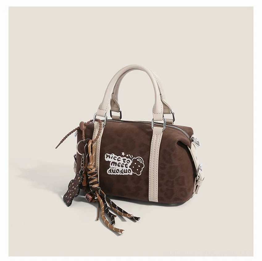 Front view of dark brown leopard print mini barrel bag with embroidered bear detail, off-white handles and decorative tassel