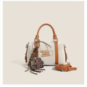 Matte white Doodle Charm mini barrel Boston bag with embroidered bear patch, contrast trim, tassel pendant and detachable shoulder strap