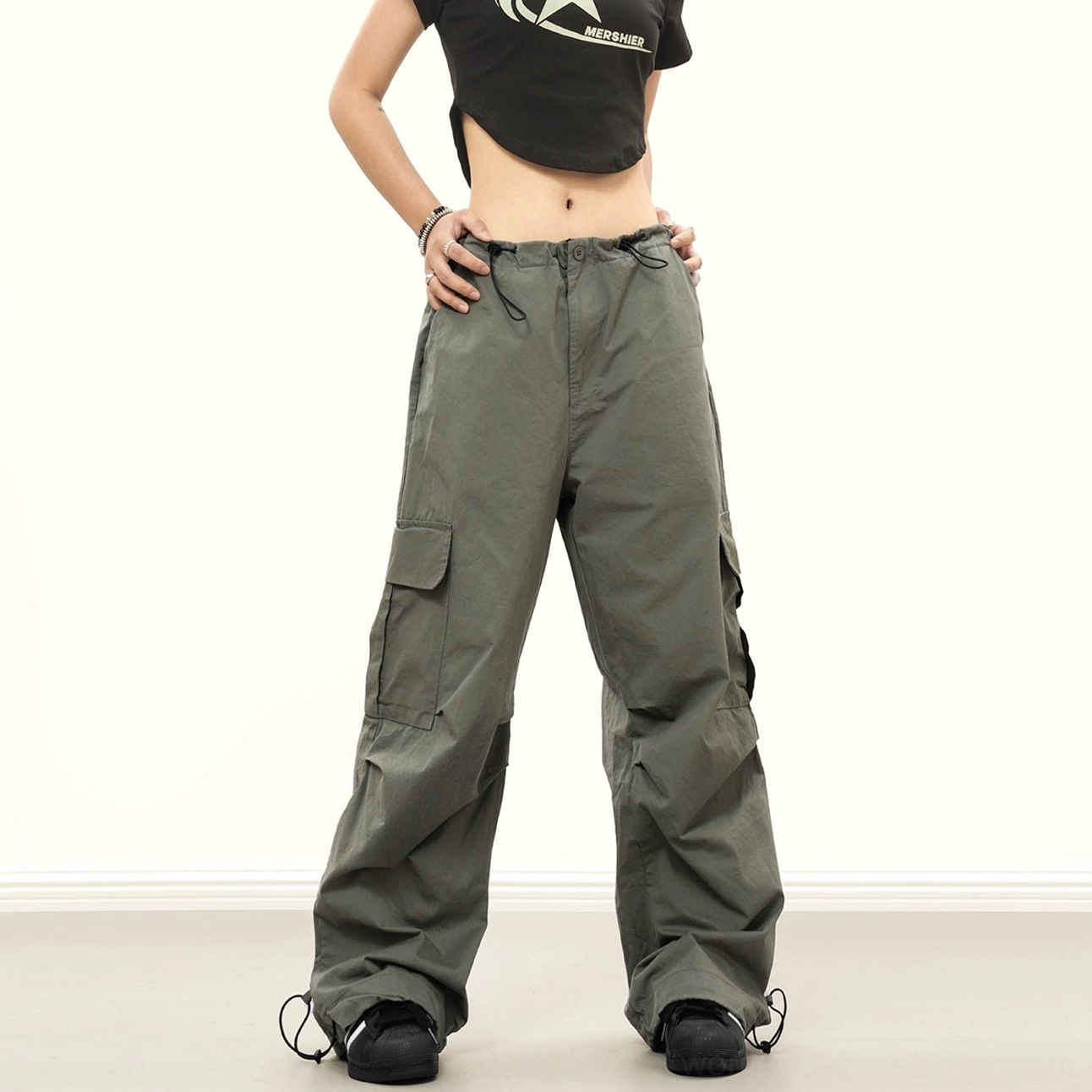Army green wide-leg baggy streetwear cargo pants styled with a cropped black top, featuring cargo pockets and drawstring cuffs