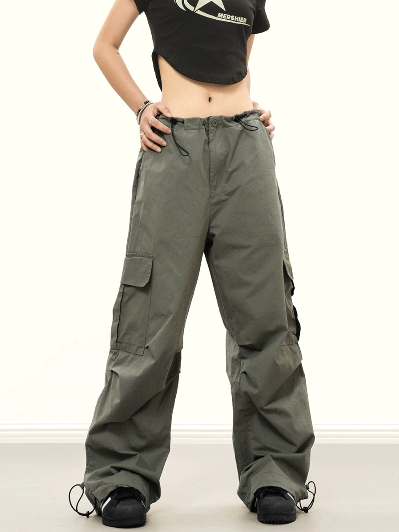 Army green baggy cargo pants with wide legs, side cargo pockets, adjustable waist drawstring and cinched ankle cuff details