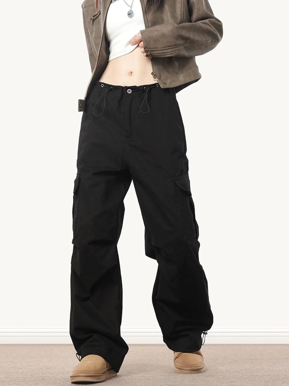 Black baggy streetwear cargo pants in a full front view with loose wide legs, drawstring waist and functional side cargo pockets