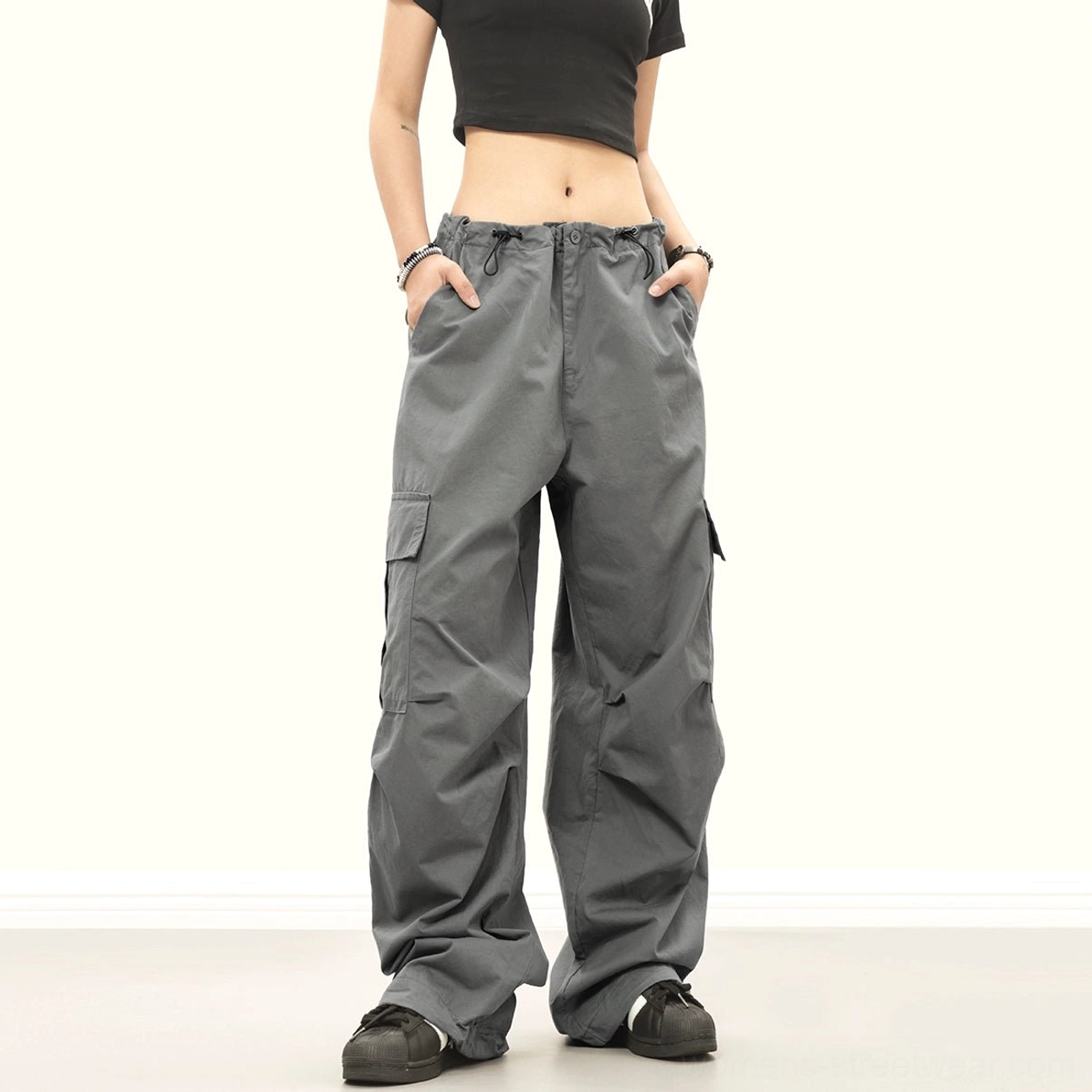 Dark gray baggy cargo pants in a relaxed streetwear fit with wide legs, side utility pockets, drawstring waist and ankle ties