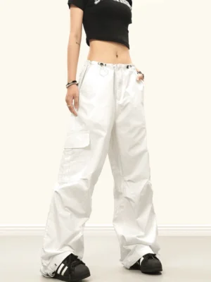 White baggy streetwear cargo pants with wide legs, side cargo pockets, drawstring waist and adjustable ankle cuffs shown in a front three-quarter outfit view