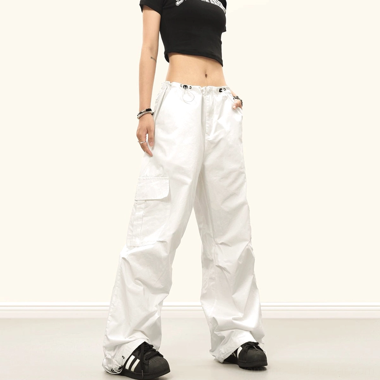 White wide-leg cargo pants with a baggy streetwear silhouette, adjustable drawstring waistband, large side pockets and ankle ties
