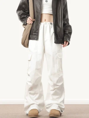 White wide-leg baggy cargo pants styled with a cropped top and leather jacket, featuring utility side pockets and an adjustable drawstring waist