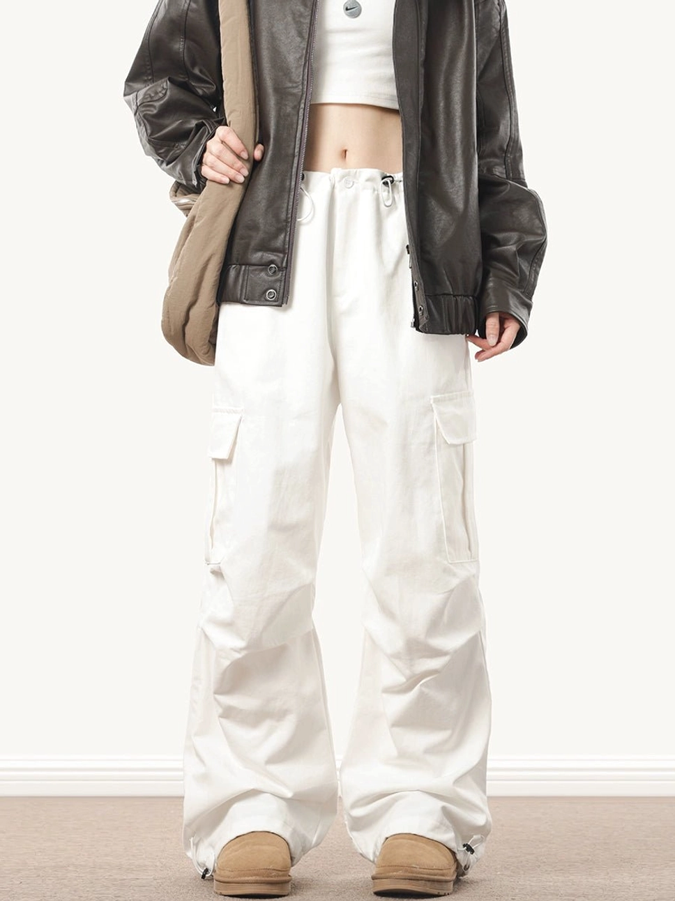 White wide-leg baggy cargo pants styled with a cropped top and leather jacket, featuring utility side pockets and an adjustable drawstring waist