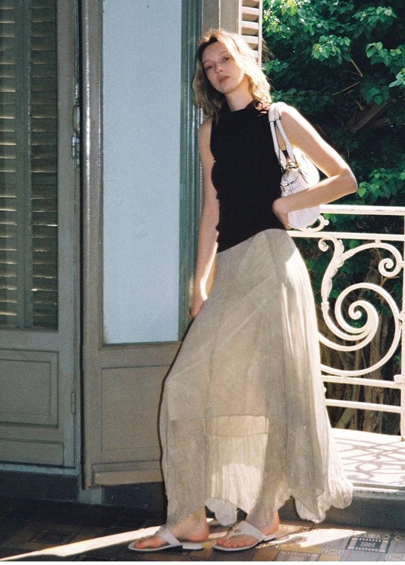 Black draped mock neck sleeveless slim fit top styled with a flowing beige maxi skirt