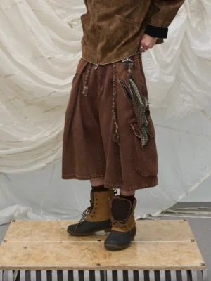 Brown washed cargo culotte shorts with oversized utility pockets, plaid scarf detail, rope trims, and workwear boots