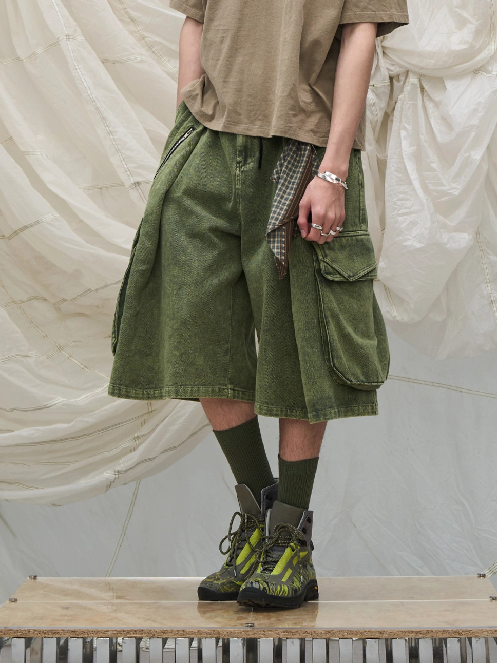 Olive green cargo culotte shorts with large side pockets, faded finish, plaid pocket detail, and relaxed wide-leg cut