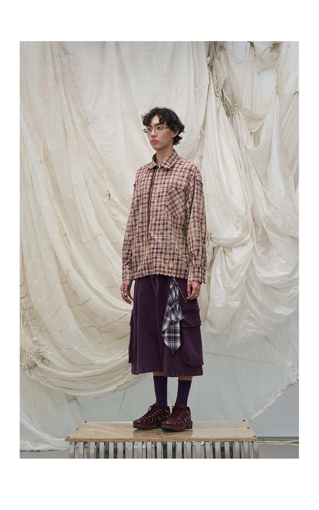 Purple cargo culotte shorts styled with a brown plaid shirt, burgundy boots, and layered scarf streetwear details